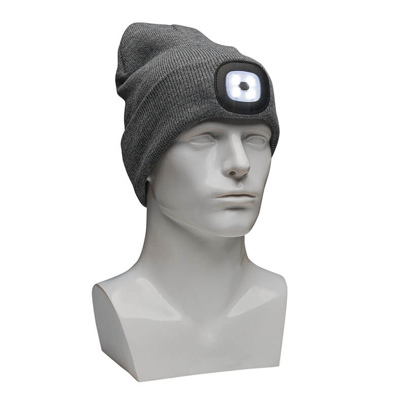 The PIP Winter Beanie Cap with LED Light 360-LED by Protective Industrial Products, in gray, is displayed on a gray mannequin head. This knit cap features a built-in LED light at the front, casting a white glow. Its slightly slouched design provides cold weather protection.