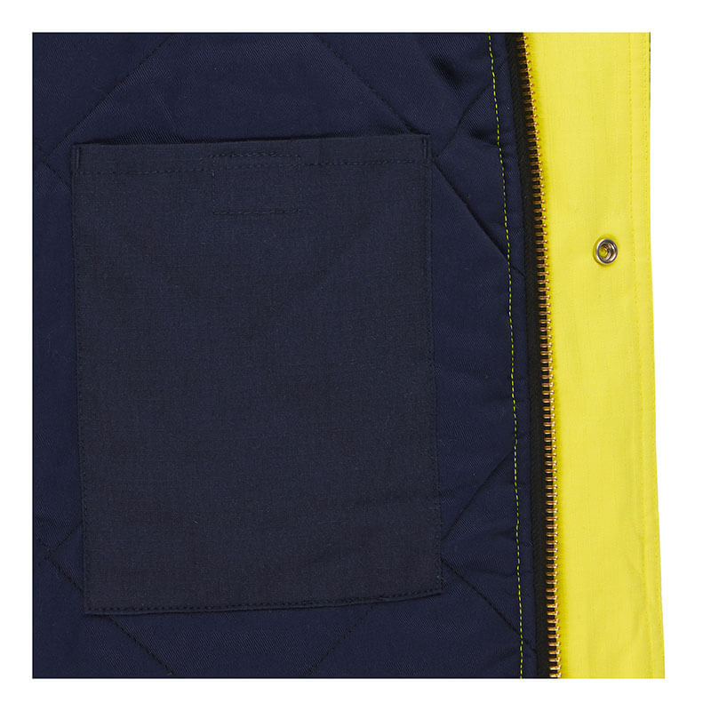 Close-up of the PIP Bisley AR/FR Inherent Insulated Parka 385M8387H showing a black inner pocket on quilted navy blue lining, with a bright yellow outer edge and yellow snap button. Brand: PIP.