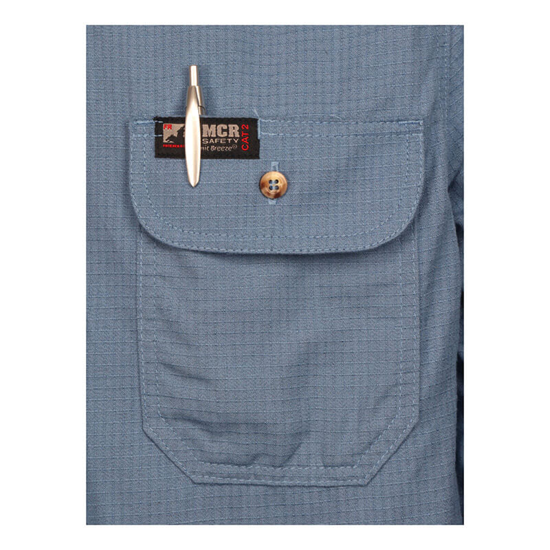 A close-up of the MCR Safety Summit Breeze 5.5 oz FR Shirt SBS100_ shows a blue textured pocket with triple vent technology, button flap, pen clip, and a black and red "MCR Safety" label above the flap.