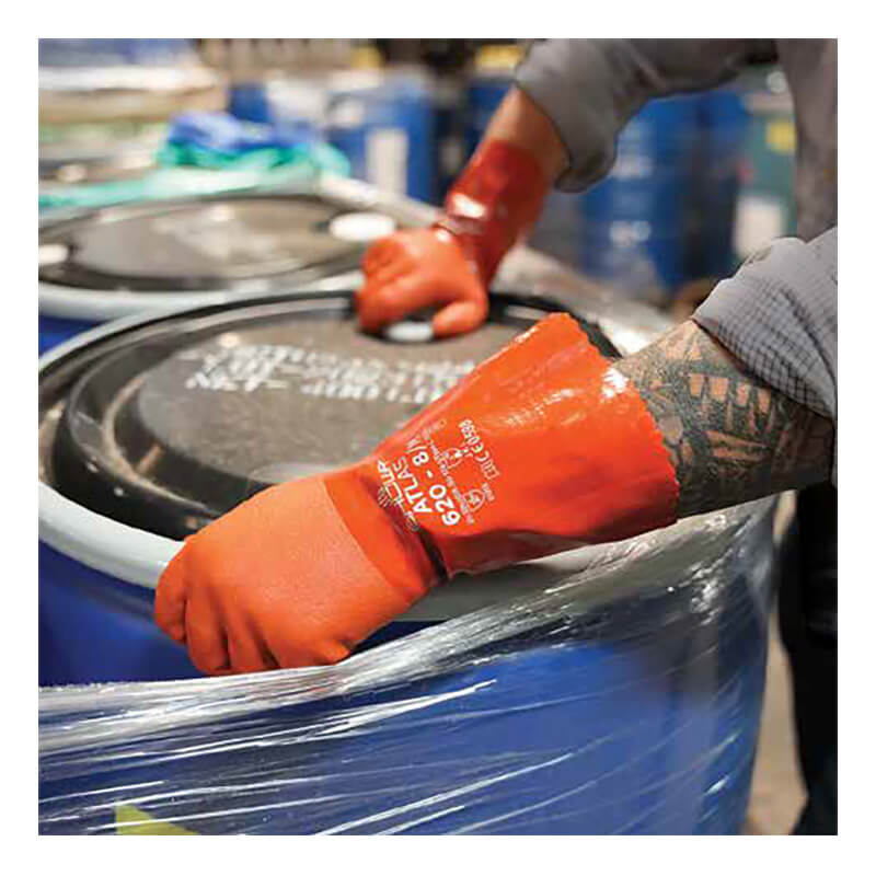 A person wearing SHOWA ATLAS 620 Chemical Gloves by Showa Best seals a black lid on a blue industrial barrel, with other similar barrels in the background.