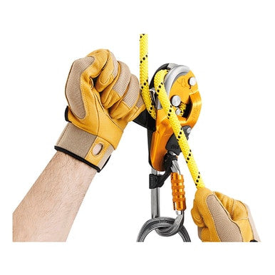 A person wearing yellow gloves is handling a yellow climbing rope with a Petzl RIG Compact Self-Braking Descender D021AA00. The ergonomic handle on this Petzl device, attached to a carabiner, enhances safety in the climbing setup against a plain white background.