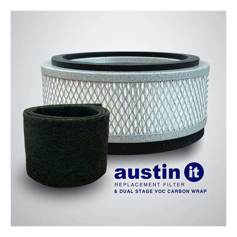 An Austin Air Systems "it" Filter and a black dual-stage VOC Carbon Wrap are shown on a light background. Below them is the text: "austin it REPLACEMENT FILTER & DUAL STAGE VOC CARBON WRAP.