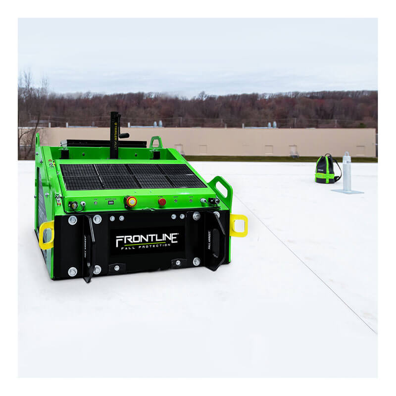 A green and black Frontline Fall Protection Solar Panel System for Commando Tank SLR-PAN sits on a white rooftop, with a Commando Tank safety harness and anchor visible in the background beneath an overcast sky and trees.