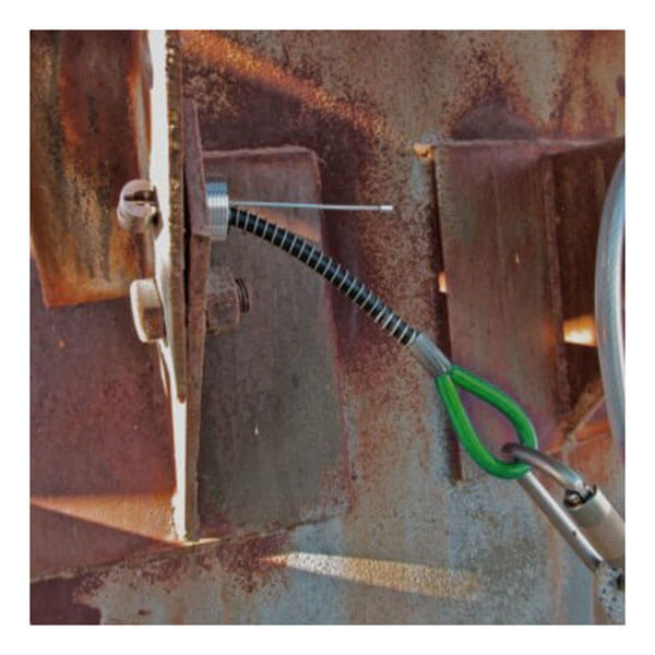 A coiled steel safety cable with a green and silver carabiner is attached to a rusty structure using the Frontline Reusable 5K Concrete & Steel Anchor Toggle Bolt by Frontline Fall Protection, illustrating fall protection equipment setup.