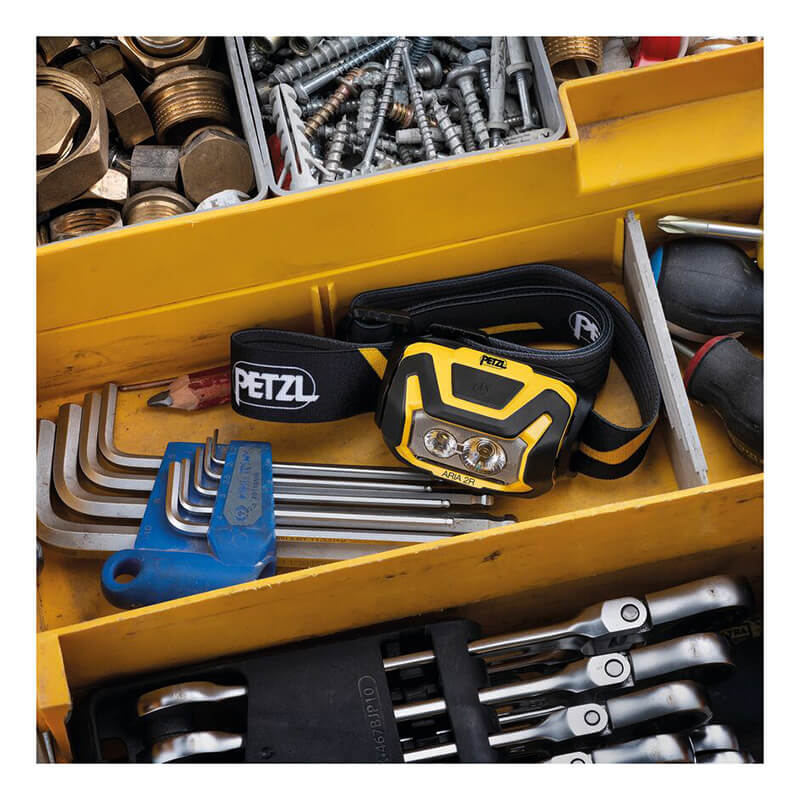 A yellow Petzl ARIA 2R Rechargeable Headlamp E070CA00, hex key set, and assorted wrenches and screws are neatly stored in a yellow toolbox.