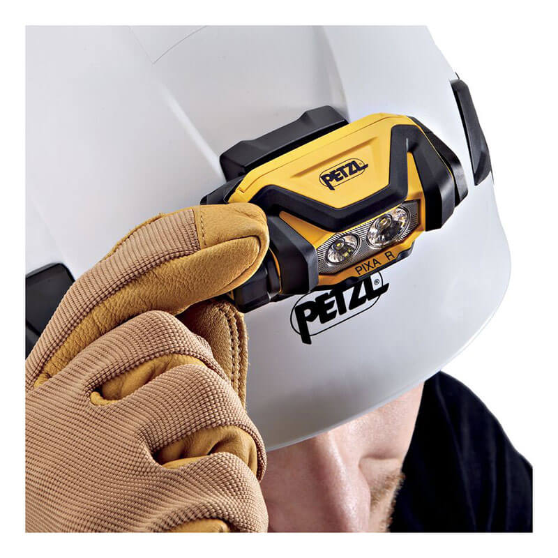 A person wearing brown gloves adjusts a Petzl PIXA R Waterproof, Rechargeable Headlamp E120CA00 attached to a white safety helmet with a black Petzl logo.