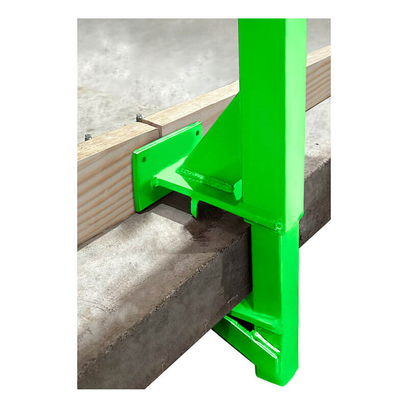 The Frontline Fall Protection Concrete Slab Grabber GUC2X4, a bright green steel bracket, anchors to concrete and secures a horizontal wooden beam as part of a perimeter edge protection system on a construction site.