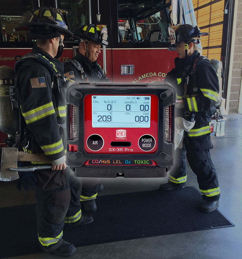 Three firefighters in full gear stand near a fire truck inside a station. An overlay shows the RKI Instruments GX-3R Pro 5 Gas Confined Space Monitor with Wireless Communication displaying air quality readings.