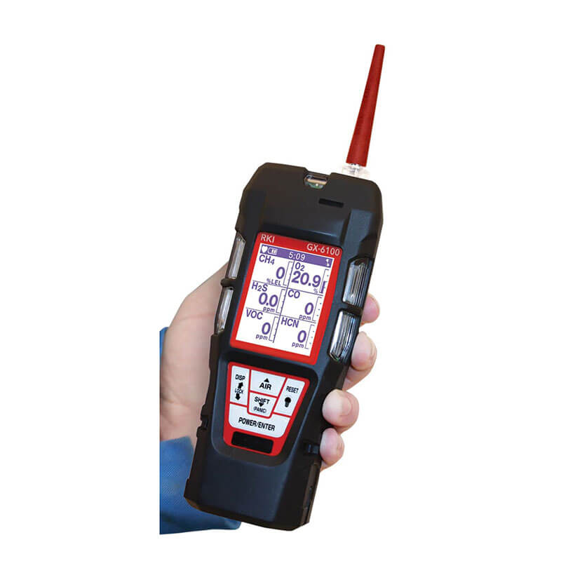 A hand holds an RKI Instruments GX-6100 Sample Draw with PID 6 Gas Monitor (72-61A_ _X-C), displaying gas levels on screen with a red probe attached—ideal for confined space entry.