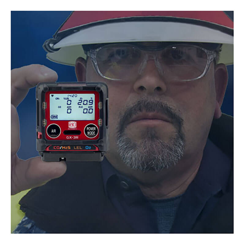 A person in safety glasses and a hard hat holds an RKI Instruments GX-3R 4 Gas Confined Space Monitor (72-RA-C), which has a digital display showing various readings.