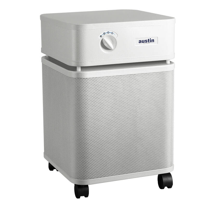 The Austin Air Systems HealthMate Plus Machine B450 is a white, square air purifier with front control knob and four wheels. It features medical grade HEPA filtration for formaldehyde removal and displays the "Austin" brand on the front panel.