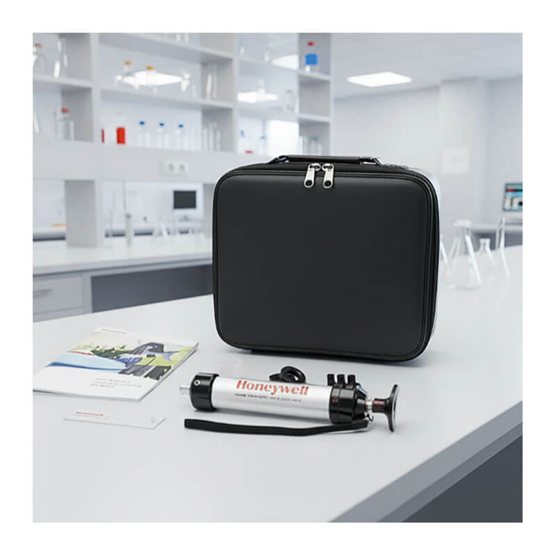 A black carrying case, colorimetric gas detection tubes, the Honeywell Piston Hand Pump by BW Technologies, and documents are on a lab table with glassware and shelves in the background.