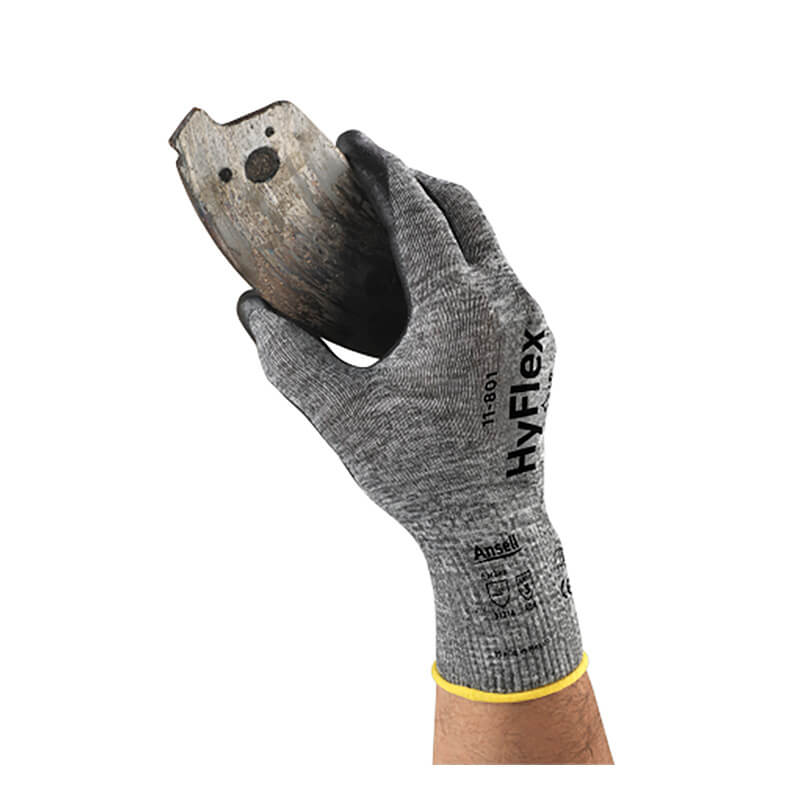 An individual wearing an Ansell HyFlex Nitrile Foam Glove 11-801 from Ansell, distinguished by its gray design and foam nitrile coating, holds a rusty, jagged piece of metal against a white background.