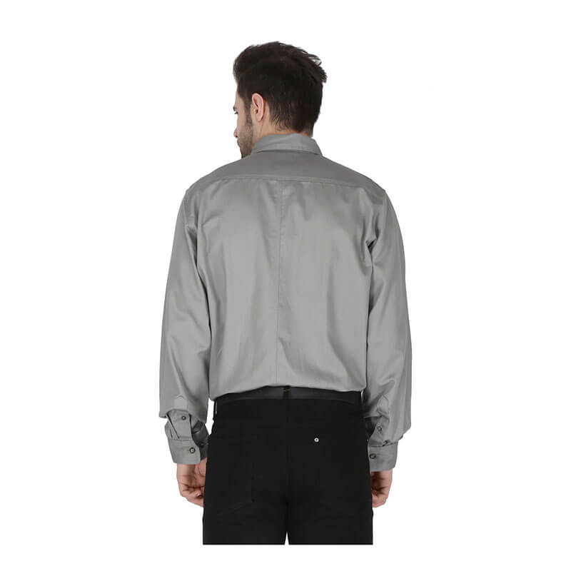 A man stands with his back to the camera, wearing a light gray ForgeFR Forge FR Solid Button Shirt MFRLB2PS024 and black pants against a white background, showcasing NFPA 2112 compliant flame-resistant style.