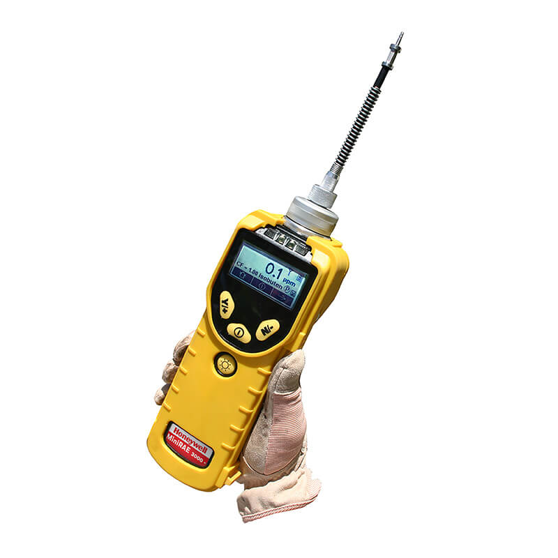 A gloved hand holding a RAE Systems MiniRAE 3000+ PGM-7320 gas detector with a digital display, antenna, and control buttons, isolated on a white background.
