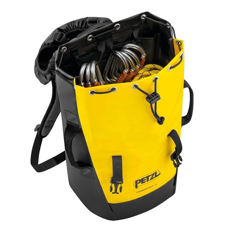 A Petzl TRANSPORT backpack in yellow and black, filled with climbing gear like carabiners and ropes, is displayed with its drawstring top open. This comfortable pack boasts adjustable straps, durable handles, and a sturdy design made from TPU tarp material, making it perfect for outdoor activities.
