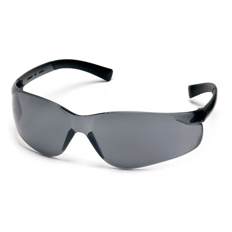 The Pyramex Ztek Safety Glasses S2510S, featuring a sleek black wraparound design with dark tinted lenses, provide UV protection and scratch resistance. The frame is smooth and shiny, crafted for both sporty and stylish appeal. These glasses are displayed at an angle on a solid white background.
