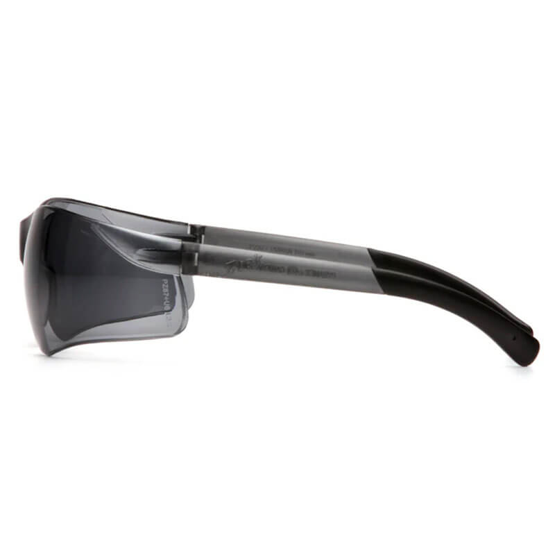 Side view of Pyramex Ztek Safety Glasses S2510S by Pyramex Safety, featuring sleek black frames, dark tinted lenses, and thick curved arms for eye and UV protection. Box contains 12 glasses.