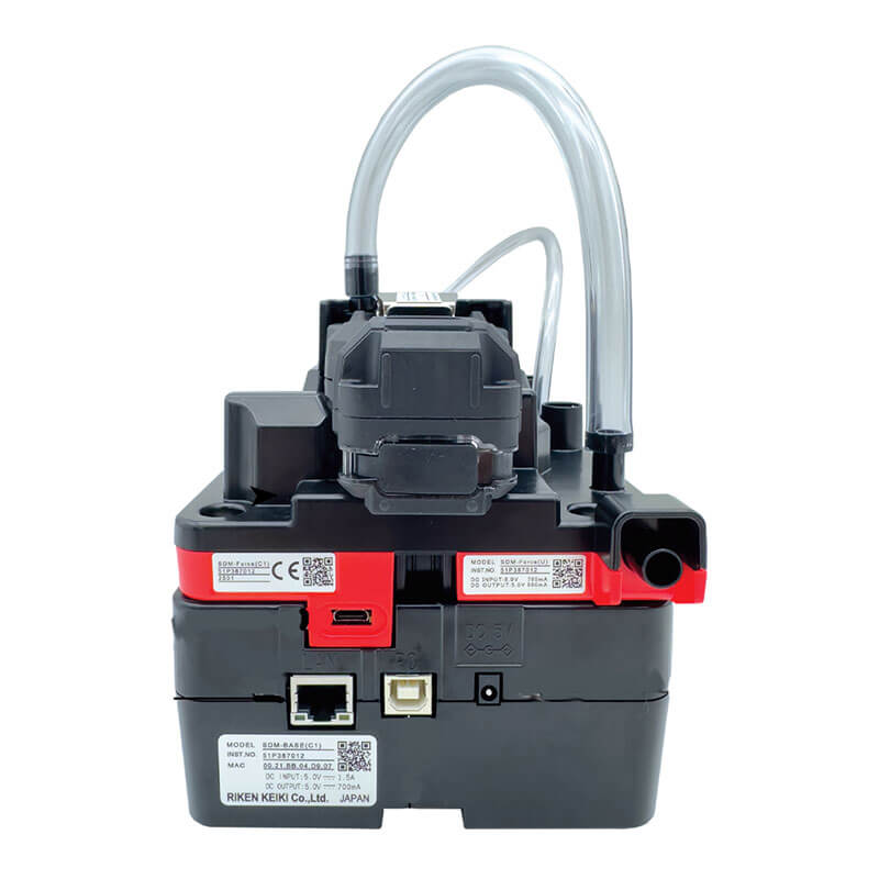 The RKI SDM-Force Calibration Station is a compact device by RKI Instruments, featuring various ports and transparent tubing on top. It has manufacturer info and QR codes, with visible USB and Ethernet ports for seamless bump testing in black and red.