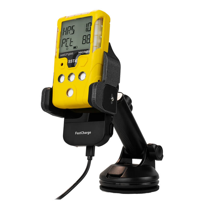 A yellow WatchGas SST Range handheld gas detector with a digital display is mounted on the WatchGas SST-CAR-CHG wireless car charger, which features a black suction cup holder and charging cable.