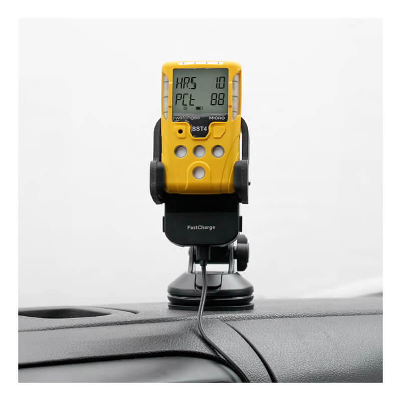 A yellow WatchGas SST Range device with a digital display is held by the WatchGas SST Range Wireless Car Charger SST-CAR-CHG, mounted on a car dashboard via suction cup and powered by a USB cable. The device screen shows numbers and abbreviations.