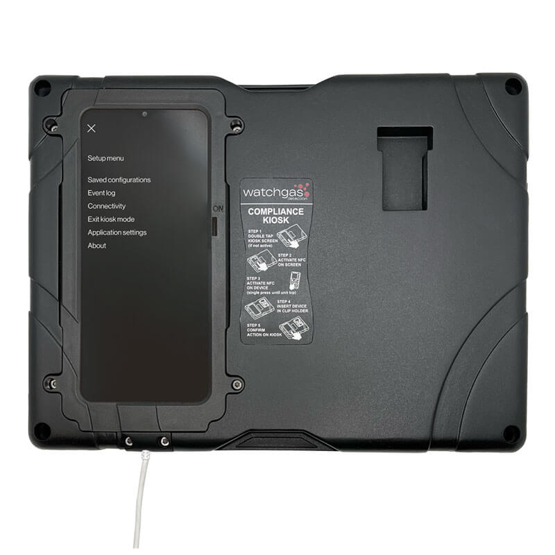 The WatchGas SST Kiosk SST-KIOSK is a black compliance device with a touchscreen setup menu on the left, a gas detector compliance instructions label on the right, and a cable attached at the bottom.