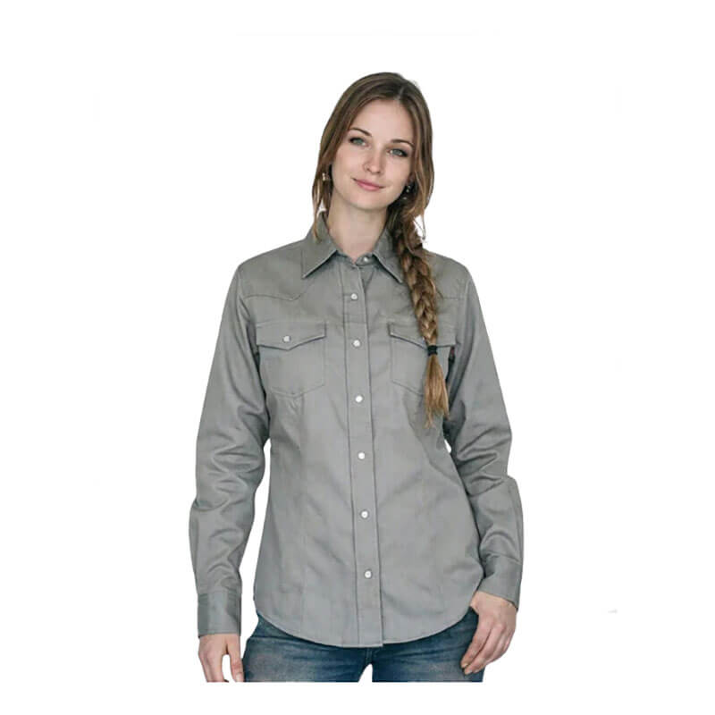 A woman with long braided hair is wearing the ForgeFR Forge FR Ladies Solid Snap Shirt LFRSLD in light gray and blue jeans, standing against a plain white background.