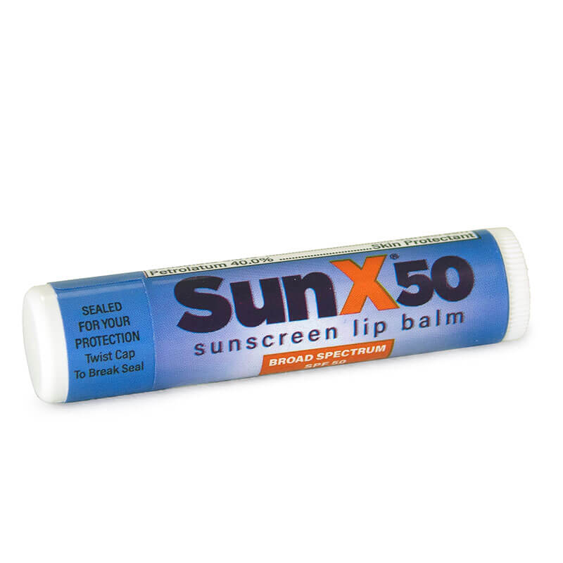 A Coretex Sun X SPF 50 Lip Balm tube from the 15ct Travel Bag lies on its side, featuring a blue label and white cap. The label notes it's sealed for protection and offers broad spectrum UV defense.