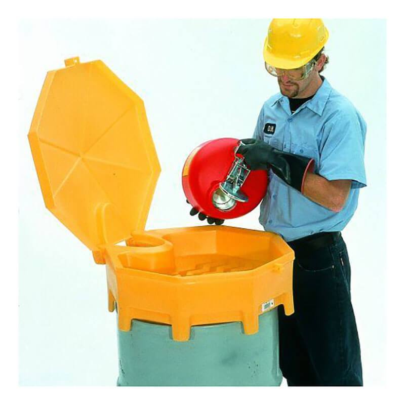 A person in safety gear, including a helmet and gloves, carefully pours liquid from a red container through an UltraTech Global Funnel 049_ into a large yellow waste disposal bin with the lid open.