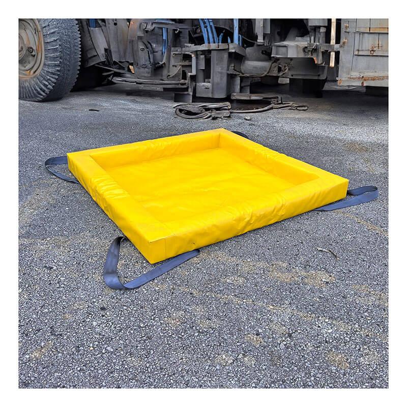 A bright yellow, square UltraTech Containment Berm - Foam Wall XC Model 898 sits on asphalt near a large industrial vehicle, with black straps extended from its corners.