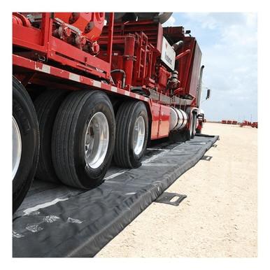 A large red truck with multiple wheels is parked on an UltraTech Foam Wall Model Containment Berm by UltraTech, on a gravel surface under a partly cloudy sky.