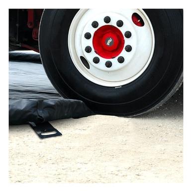 A close-up of a truck tire beside an UltraTech Foam Wall Model Containment Berm by UltraTech on concrete. This berm is designed to stop leaks or spills from reaching the ground.