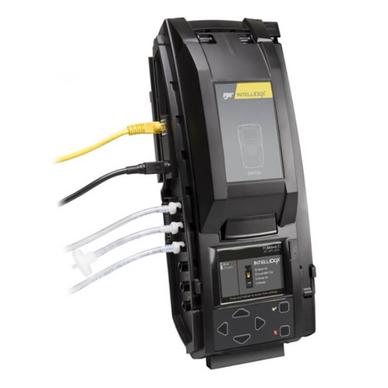 A sleek black electronic device featuring an LCD display and ethernet, along with multiple ports for various cables, is identified with the branding of PK Safety Supply. This device operates as a BW IntelliDoX Docking Station for 4-Gas Monitors DX-MCLP. Its control is facilitated by buttons, and the array of connected cables suggests its application in network or technical environments like a calibration station.