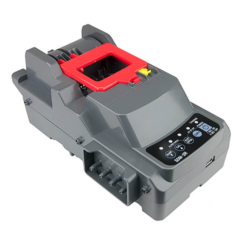 The RKI SDM-3R Stand Alone Calibration Station 81-SDM3R101 is a robust industrial device with a USB port and various connection points, ideal for any setup. Its gray and red design closely resembles a calibration station, featuring buttons, indicators, and a prominent red component on top.