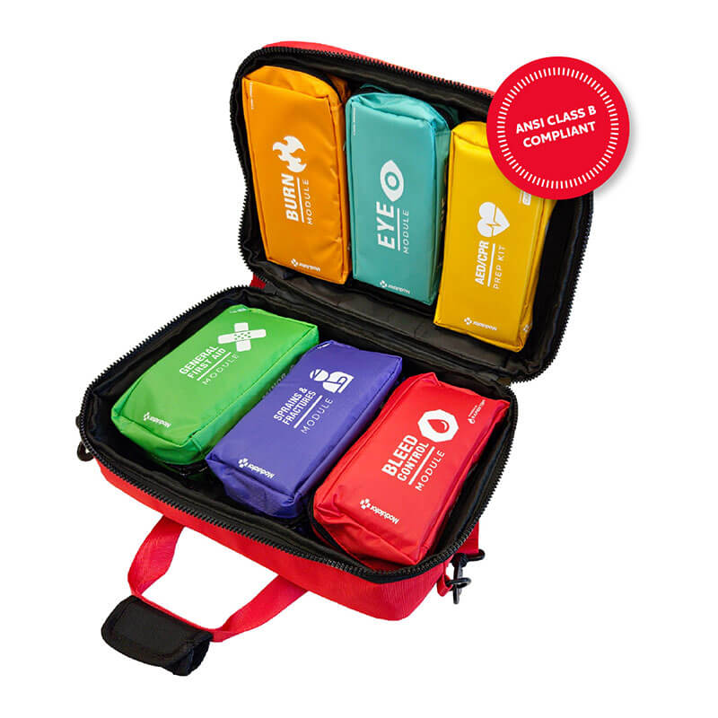The Aero Healthcare Modulator Emergency Response Bag M610B, resembling an AED/CPR Prep Kit, is open to reveal six color-coded pouches for burns, eye injuries, medications, wound care, fracture/sprain, and bleeding. It is ANSI Class B compliant.