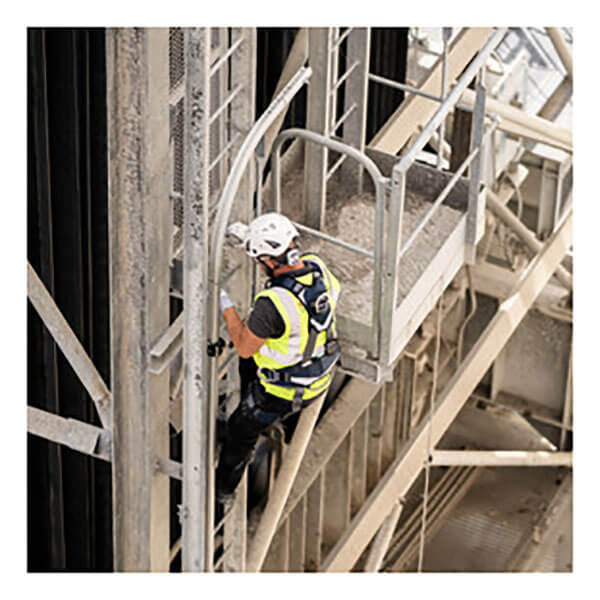 A worker wearing PPE climbs a vertical ladder equipped with the Frontline Securail Pro Vertical Lifeline System VLRS by Frontline Fall Protection, attached to an industrial structure with a nearby metal platform and guardrails.