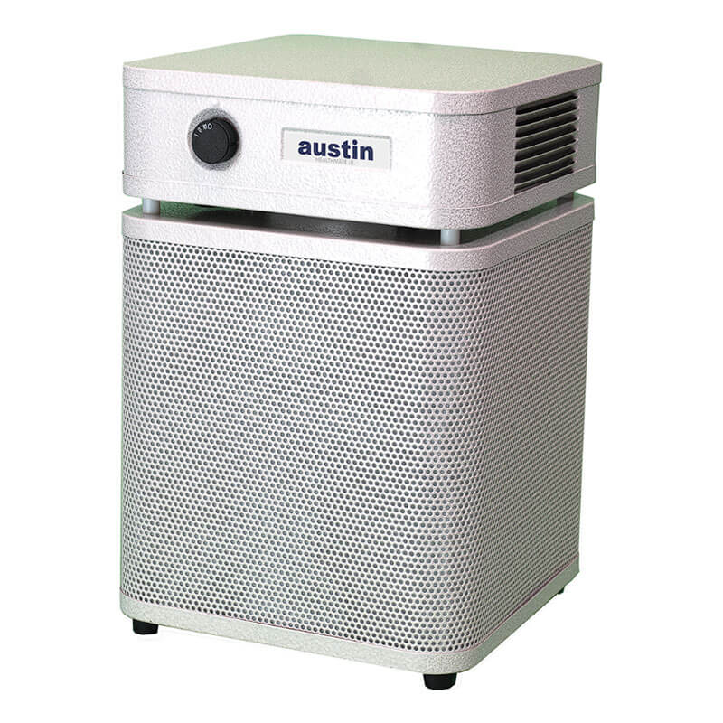 The white Austin Air Systems HealthMate Junior Machine A200, featuring a boxy design, black front control knob, and side vent, sits on a flat surface—ideal for reducing allergies.