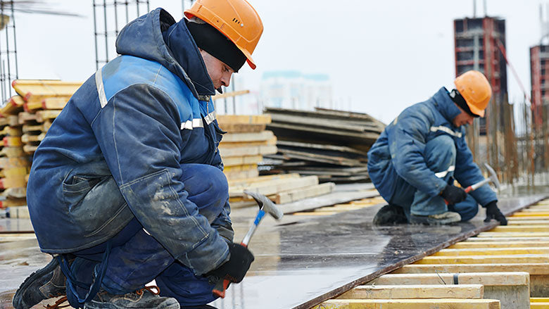 Construction workers bundled up in winter workwear at the jobsite.