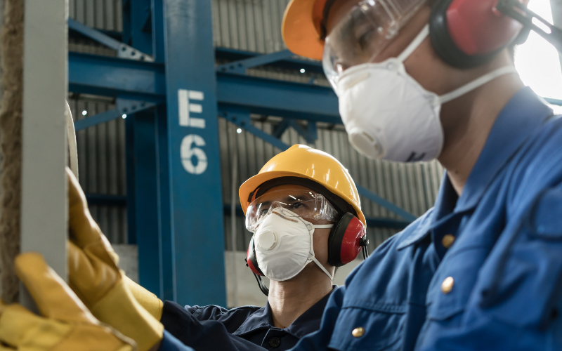 Two workers wearing PPE while insulating an industrial pressure vessel.