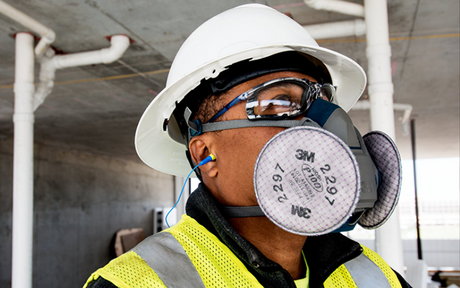 Construction worker wearing half-mask respirator, hard hat, and safety glasses.