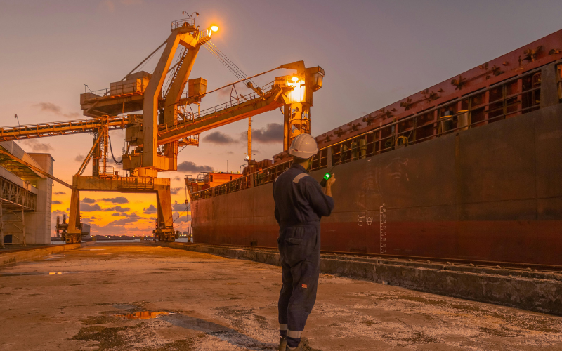 Dock Worker Inspecting Cargo Ship at Sunset