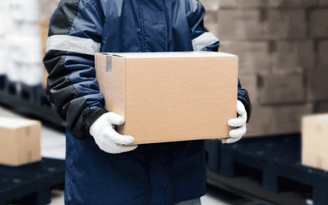 Worker in warm jacket and thick gloves, carrying a box.