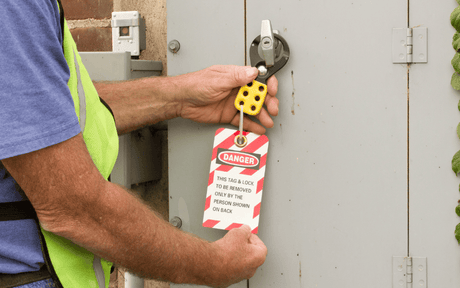 Man attaching lockout tag to outside of electrical control panel.