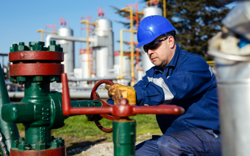 Oil worker turning valve on oil rig