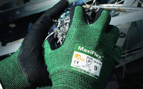Green safety gloves holding metal shards.