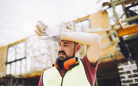 Construction worker wiping off sweat from his head.