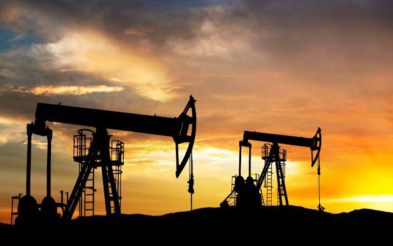 Silhouettes of oil rigs at sunset.