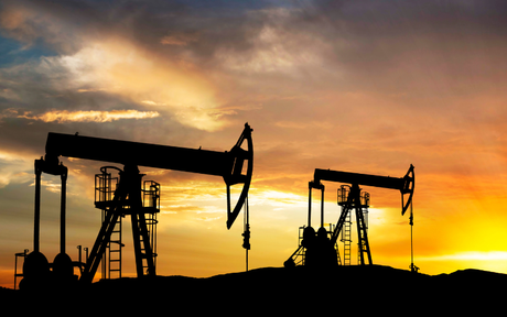 Silhouettes of oil rigs at sunset.