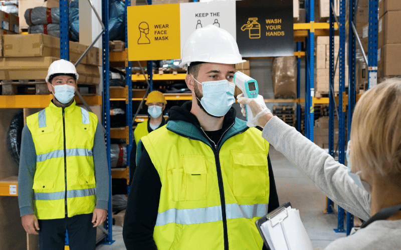 Group of Workers with Face Mask in Warehouse, Coronavirus and Temperature Measuring Concept.