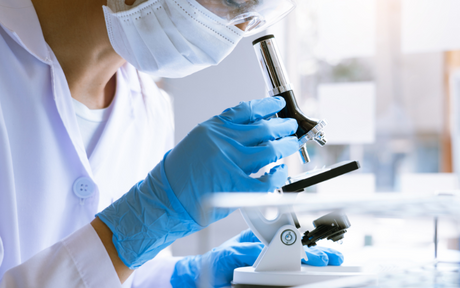 Worker conducting medical research wearing medical safety gloves.